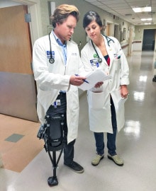Dr Ryan Logan wearing an iWALK crutch at a hospital while speaking to another doctor - iWALKFree
