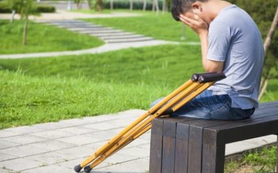 Injured Man with crutches sitting on a bench