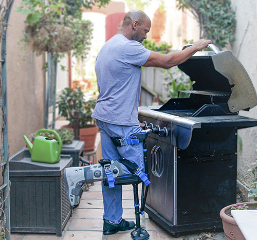 Lifestyle image of a man standing at the barbecue while wearing the iWALK hands-free crutch iWALKFree